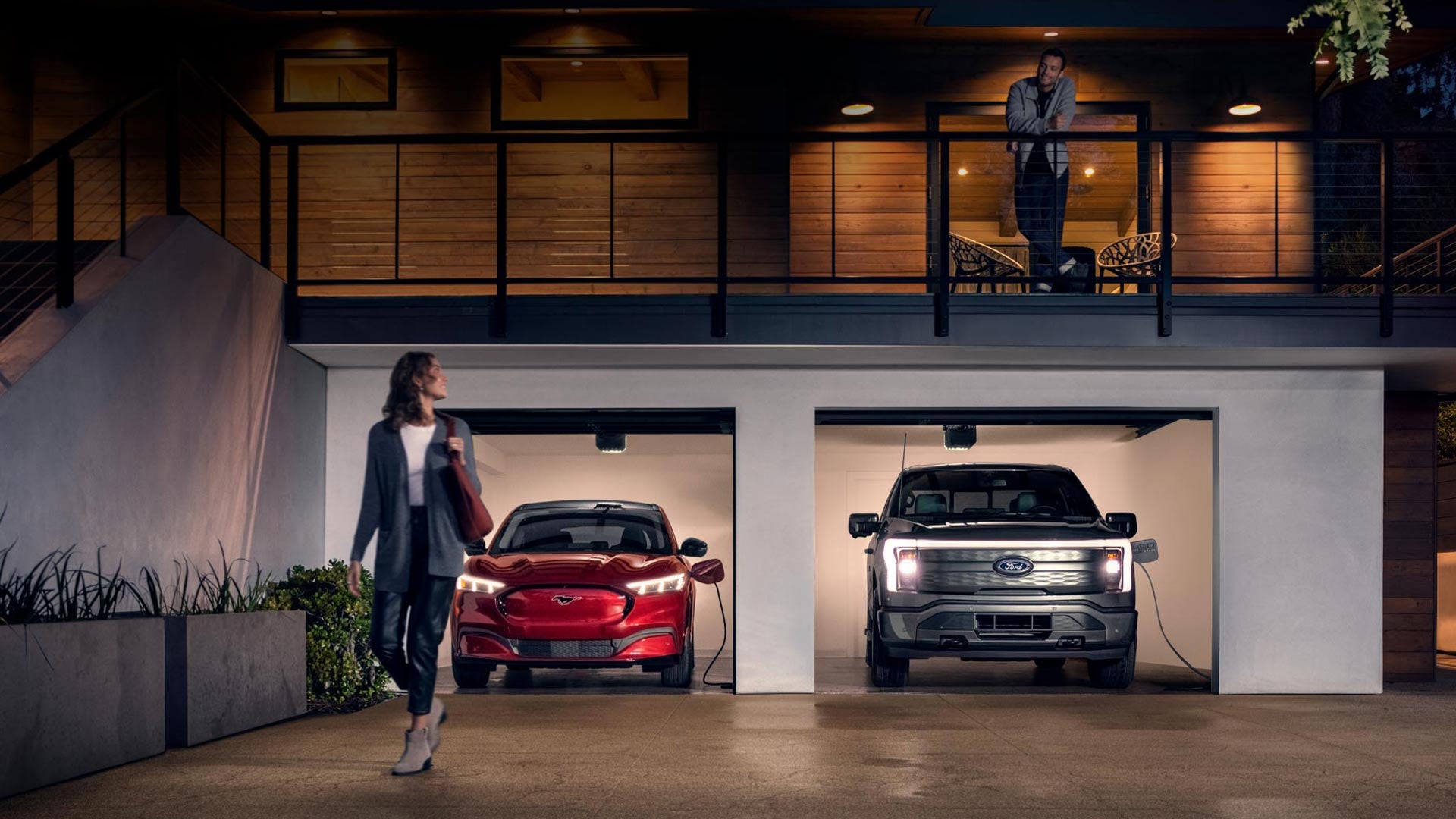 Woman walking out from home garage with a 2024 Mustang® Mach-E and Ford Lightning® truck in plugged-in and charging | Pines Ford in Pembroke Pines FL
